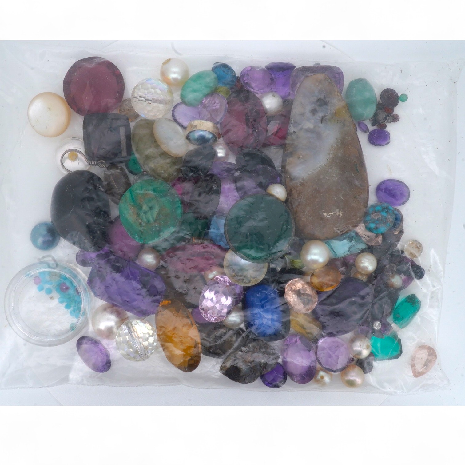 A bag of loose stones, including amethysts, garnets, cultured pearls, a quantity of small diamonds and rubies, jadeite beads, a green chrysoprase intaglio depicting the cathedral of St Stephen, Vienna, and various synthe